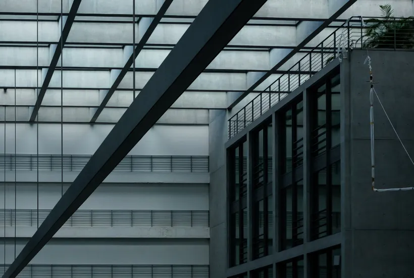 Modern architectural interior featuring a sleek glass ceiling, concrete walls, and geometric structures, relevant to cryptocurrency and gaming themes.